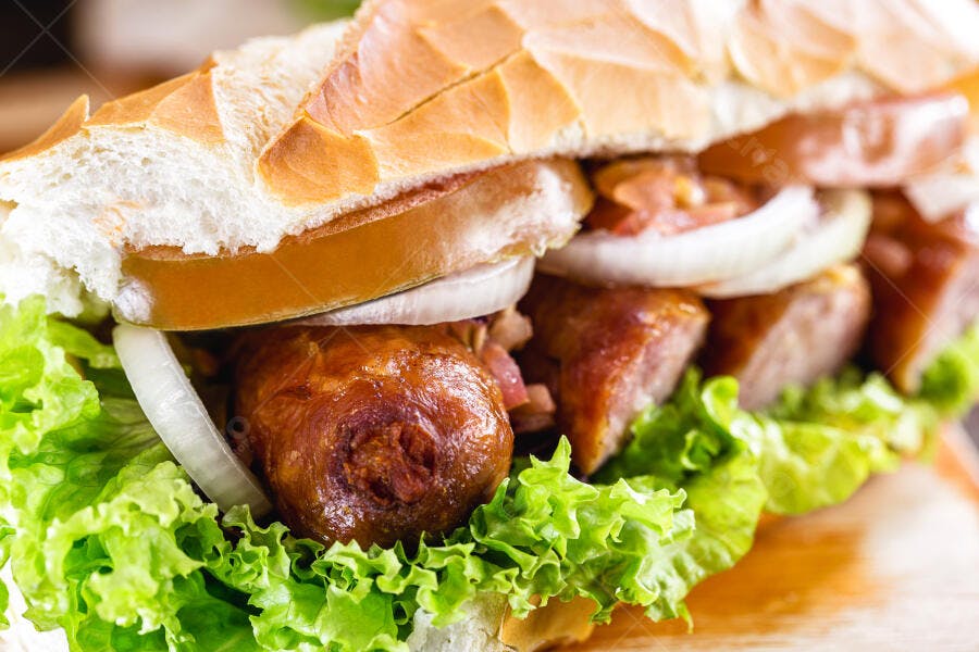 Pão francês com linguiça grelhada, alface e cebola fresca