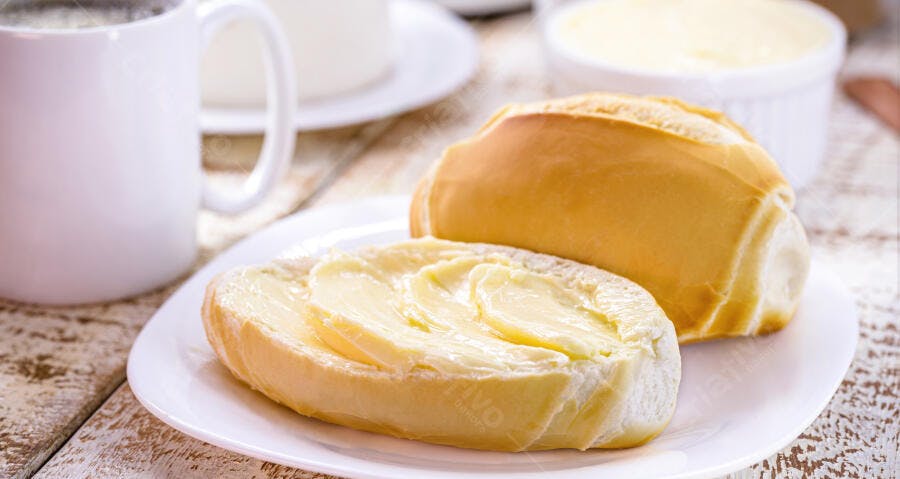 Pão francês com manteiga e café na mesa de madeira rústica para café da manhã