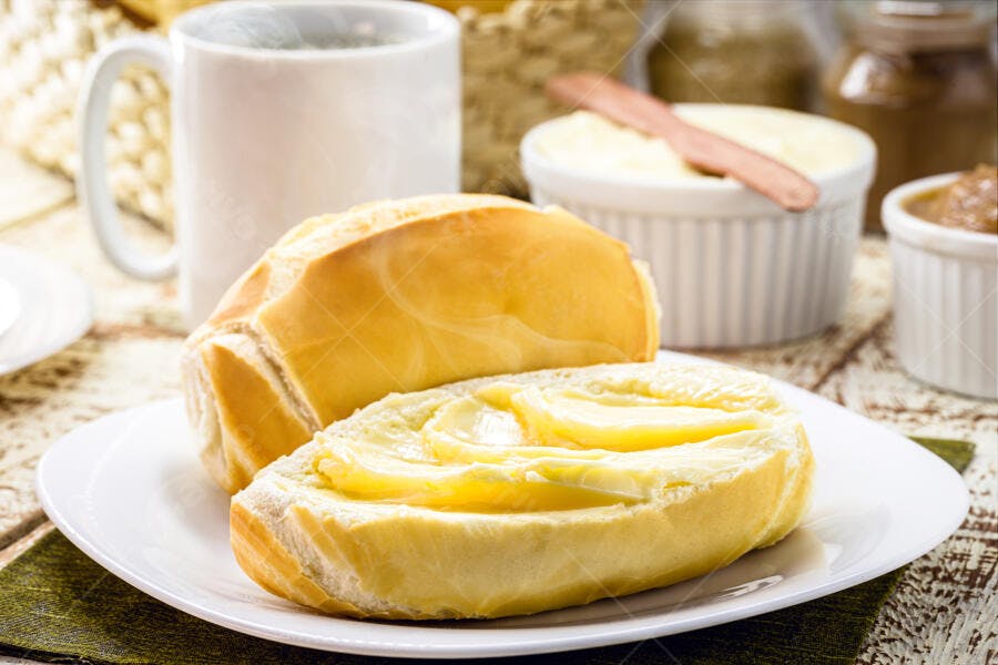 Pão francês com manteiga no café da manhã na mesa de madeira