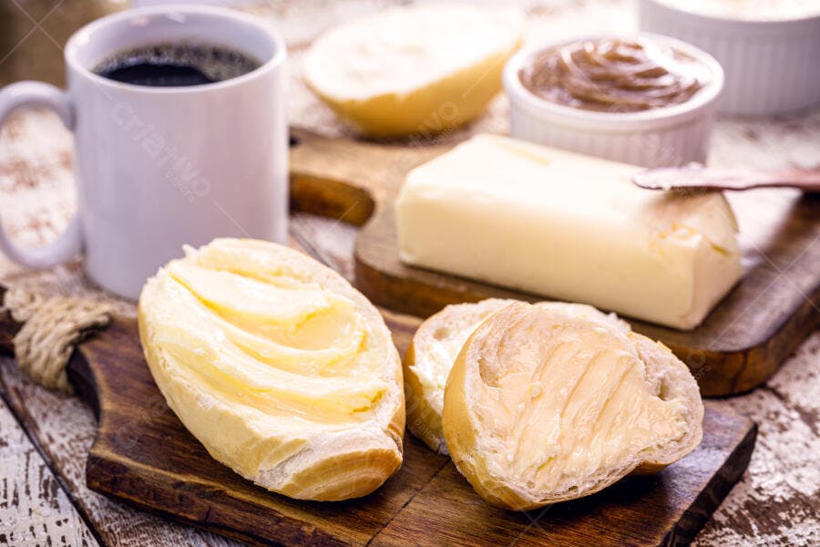 Pães franceses com manteiga e café da manhã rústico na mesa