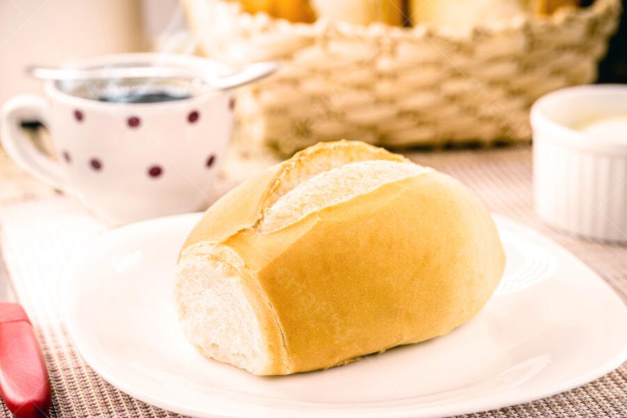 Pão francês dourado em prato branco para café da manhã aconchegante