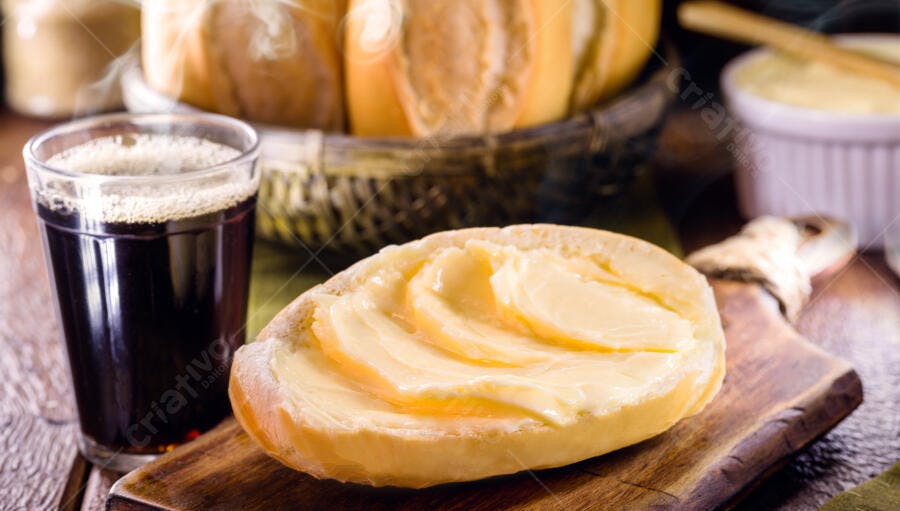 Pão francês cortado com manteiga e café quente no café da manhã