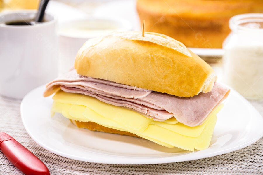 Sanduíche de pão francês dourado com queijo amarelo e presunto rosa para café da manhã