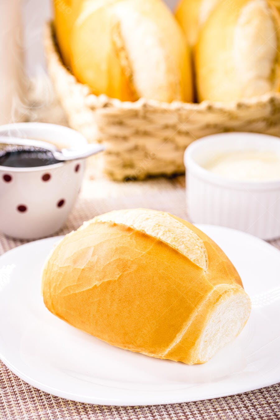 Pão francês dourado na mesa com café e manteiga para o café da manhã