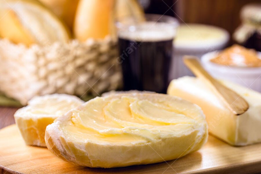 Pão francês fresco com manteiga para café da manhã em mesa de madeira rústica