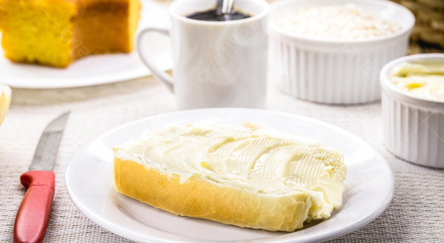 Pão com manteiga cremoso café bolo de milho e faca vermelha