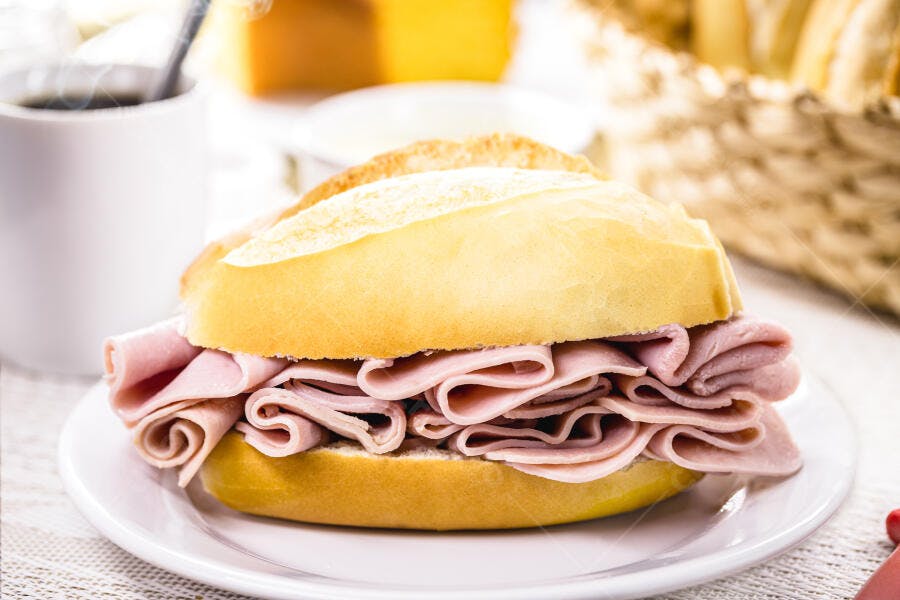 Pão francês fresco com presunto fatiado no café da manhã