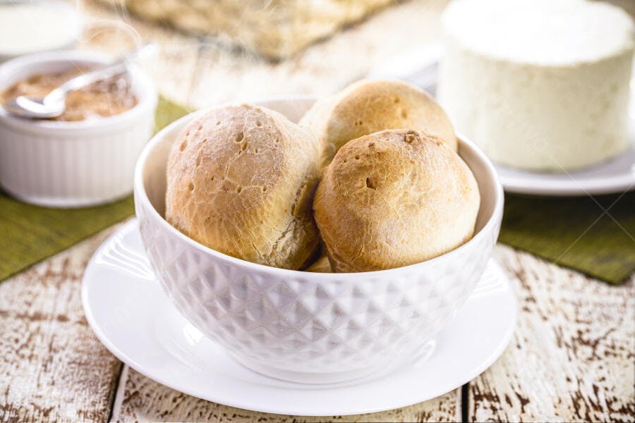 Pães de queijo quentes em tigela branca com café da manhã rústico