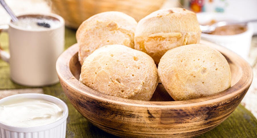 Pãezinhos de queijo fresco em tigela de madeira com café da manhã