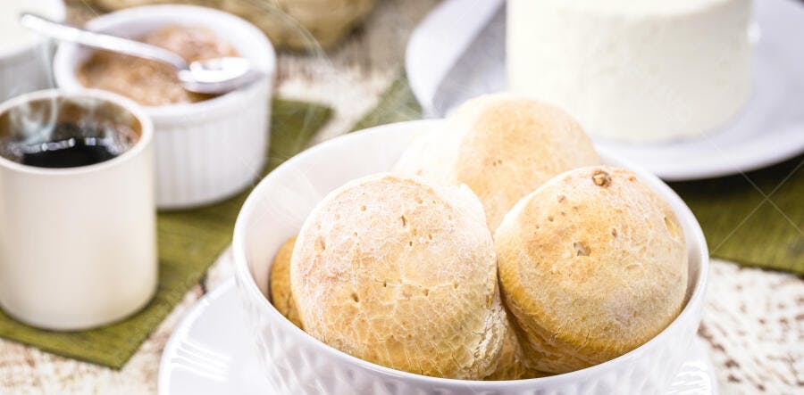 Pão de queijo fresco com café quente e queijo minas na mesa de café da manhã