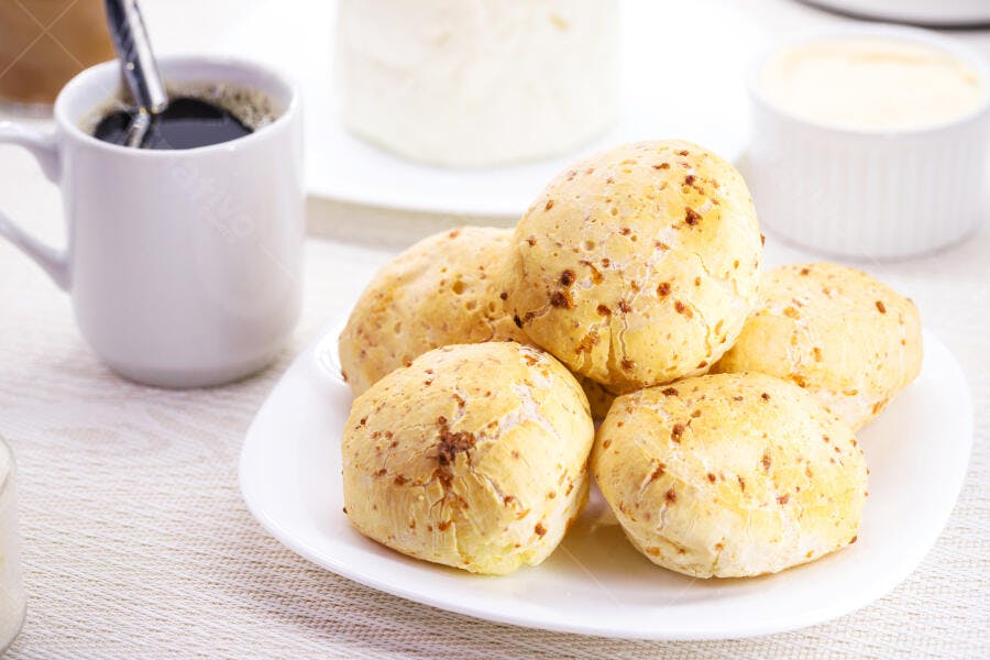 Pão de queijo fresco com café preto em mesa de café da manhã