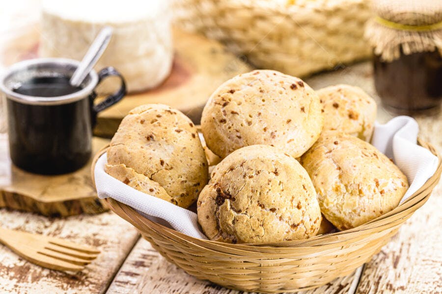 Pão de queijo fresco em cesta de vime com café e queijo tradicional