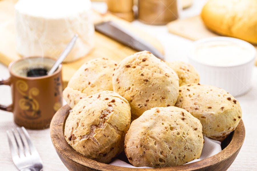 Pão de queijo fresco e café quente na mesa de café da manhã