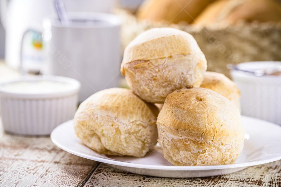 Pães de queijo frescos em prato branco para café da manhã em mesa rústica