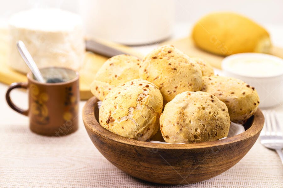 Pão de queijo quentinho em tigela de madeira com café e queijo minas frescal
