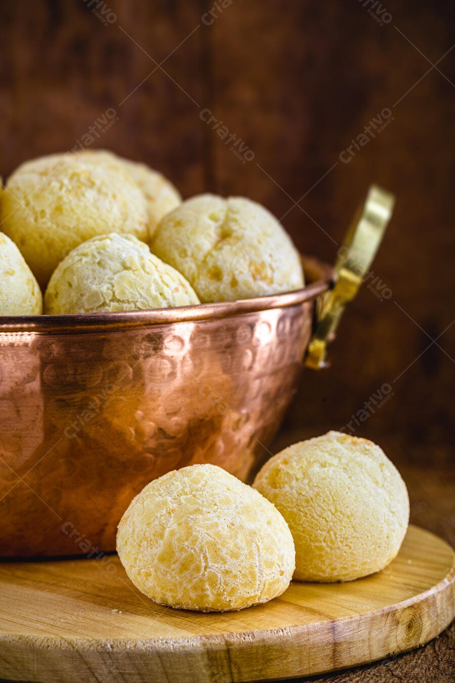 Pão de queijo fresco crocante em panela de cobre rústica sobre madeira escura
