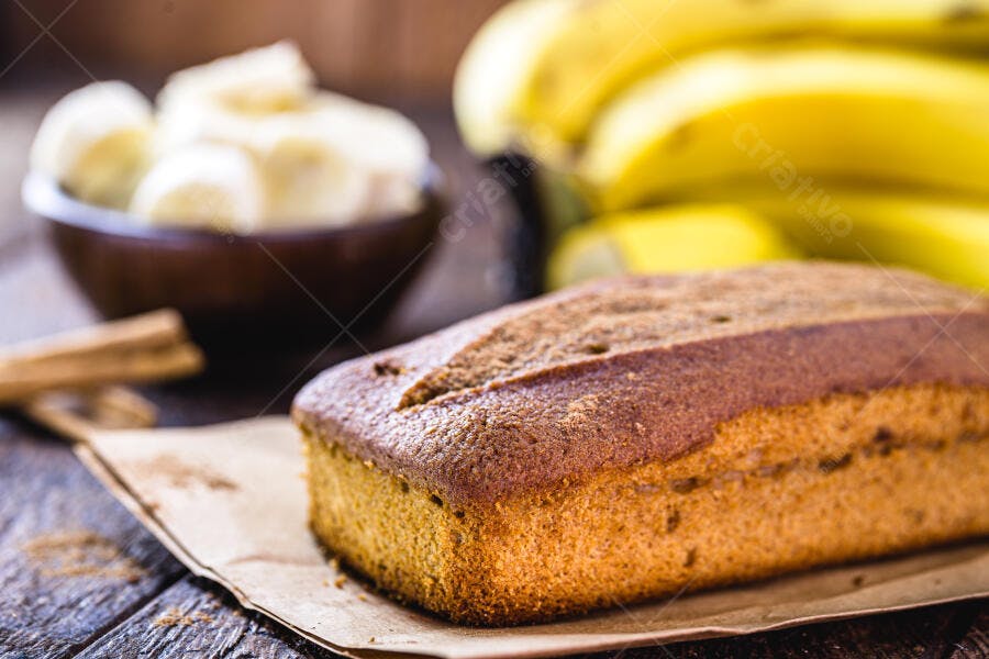 Bolo de banana caseiro com canela sobre madeira rústica e frutas amarelas