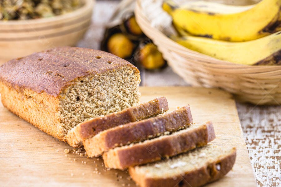 Bolo de banana caseiro fatiado em tábua de madeira rústica com bananas