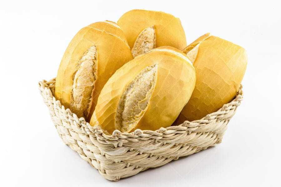Pães franceses dourados em cesta de palha fresca