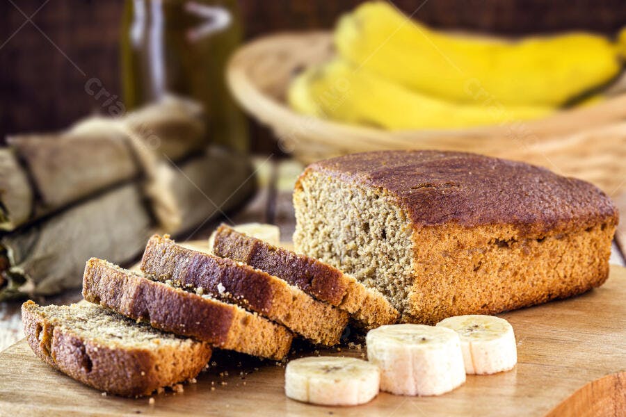 Pão de banana caseiro fatiado fresco com rodelas de fruta em mesa rústica