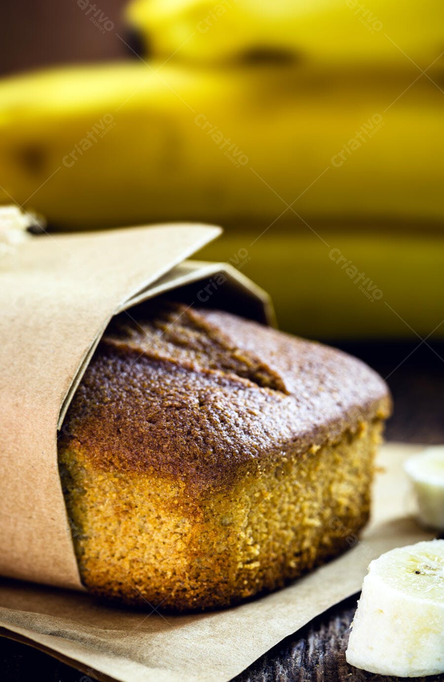 Pão de banana caseiro envolto em papel craft com fatias de fruta fresca