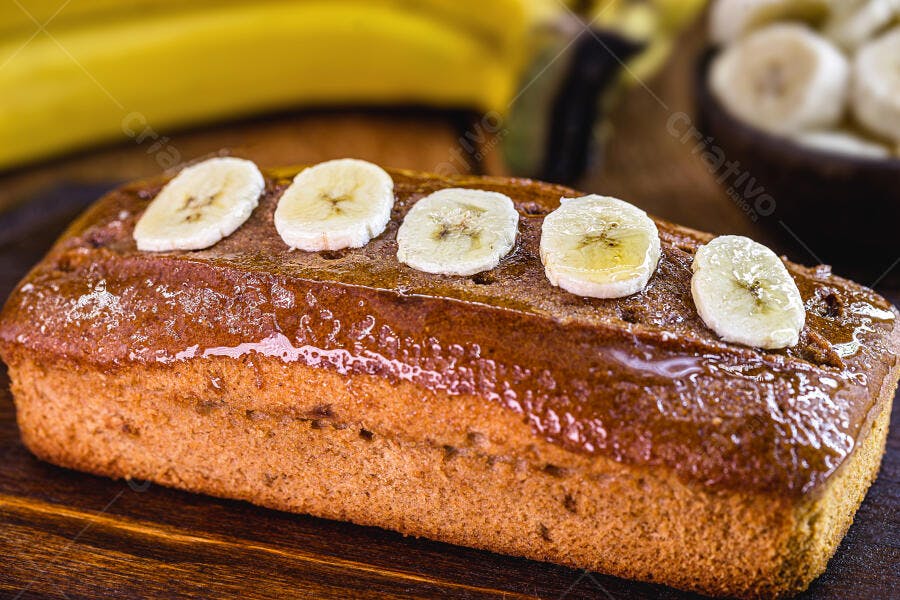 Bolo de banana caseiro com fatias frescas de fruta em cima na mesa de madeira