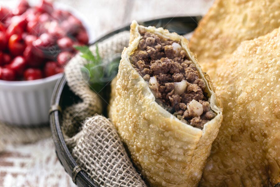 Pastel de carne aberto em cesta rústica com pimenta vermelha