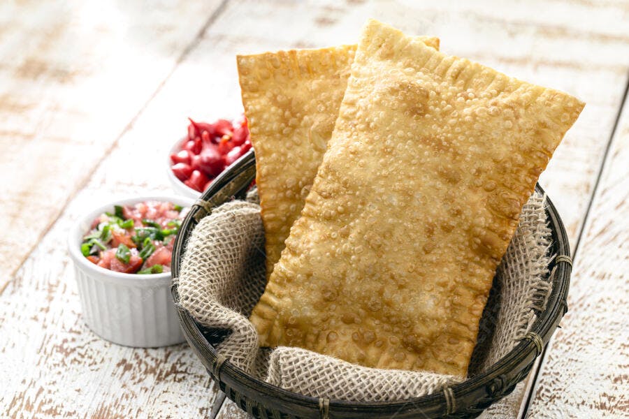 Pastéis brasileiros crocantes em cesta com vinagrete e pimenta biquinho