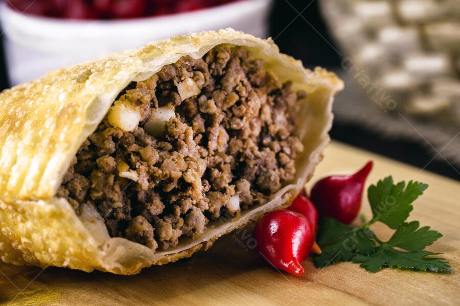 Pastel frito de carne moída aberto com pimentas biquinho e salsinha