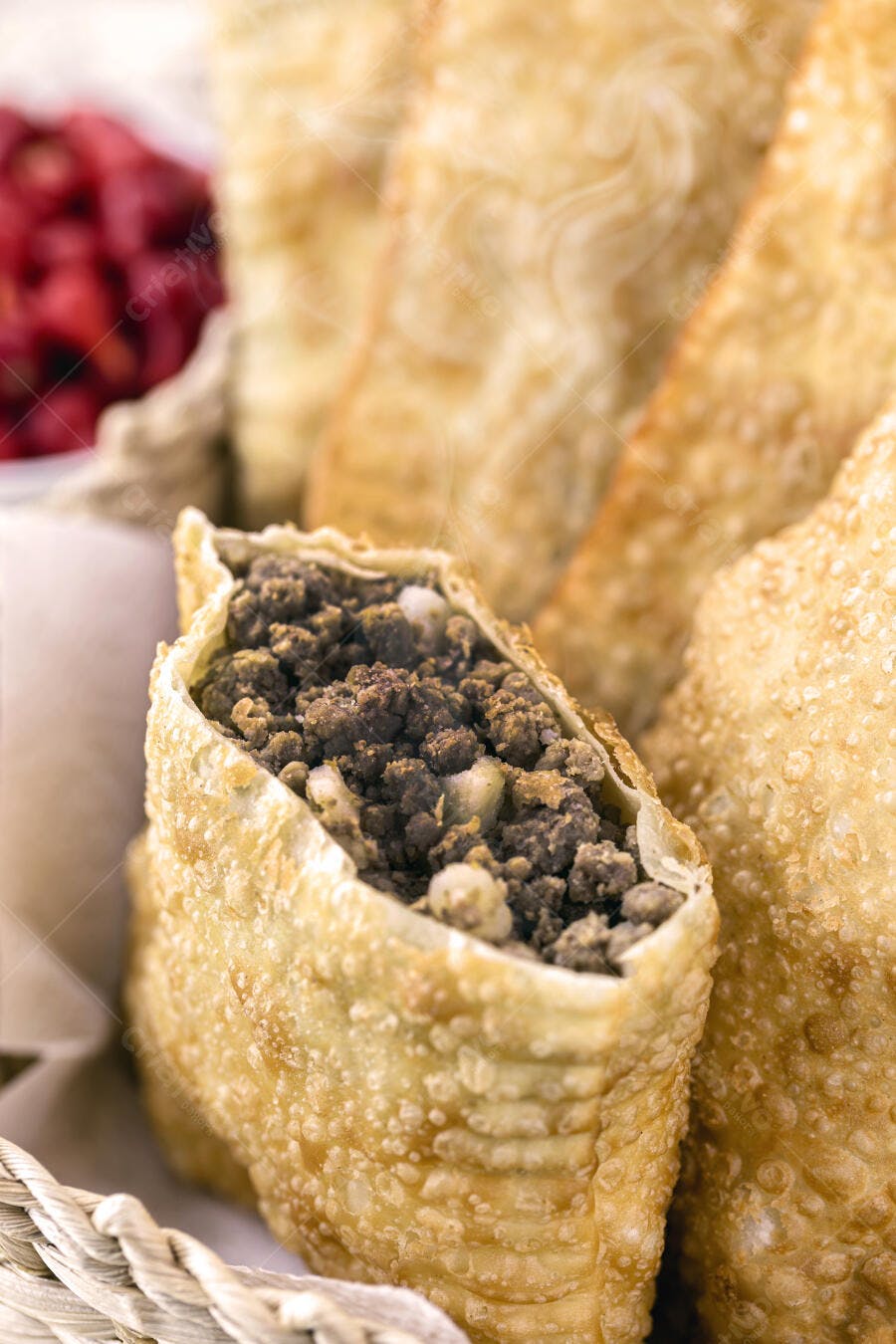 Pastel de carne moída aberto com recheio crocante em cesta de palha