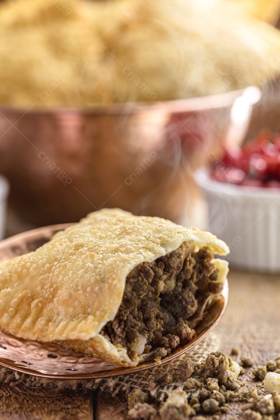 Pastel de carne frito crocante em prato de cobre em mesa rústica