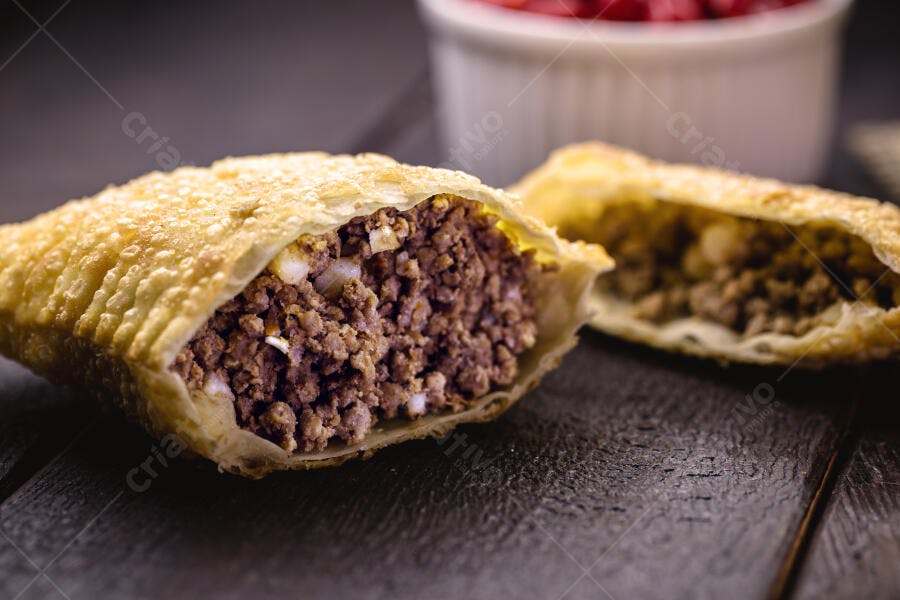 Pastel frito de carne moída com massa crocante em fundo escuro de madeira