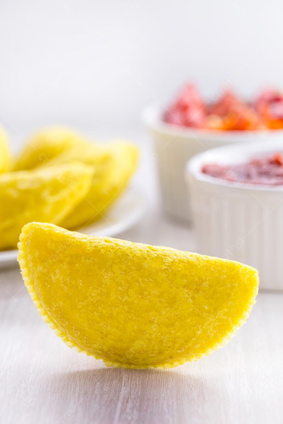 Pastel frito crocante amarelo em bancada com molhos