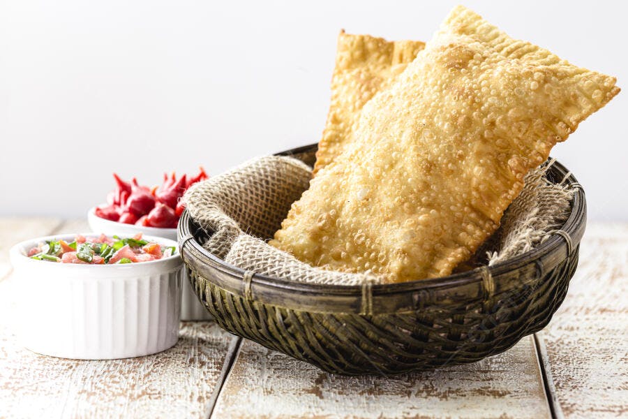 Pastéis fritos crocantes em cesta com vinagrete e pimentas vermelhas