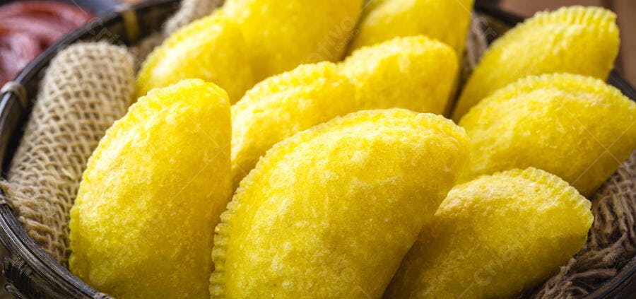Pastéis amarelos fritos crocantes em cesta de vime com forro de juta