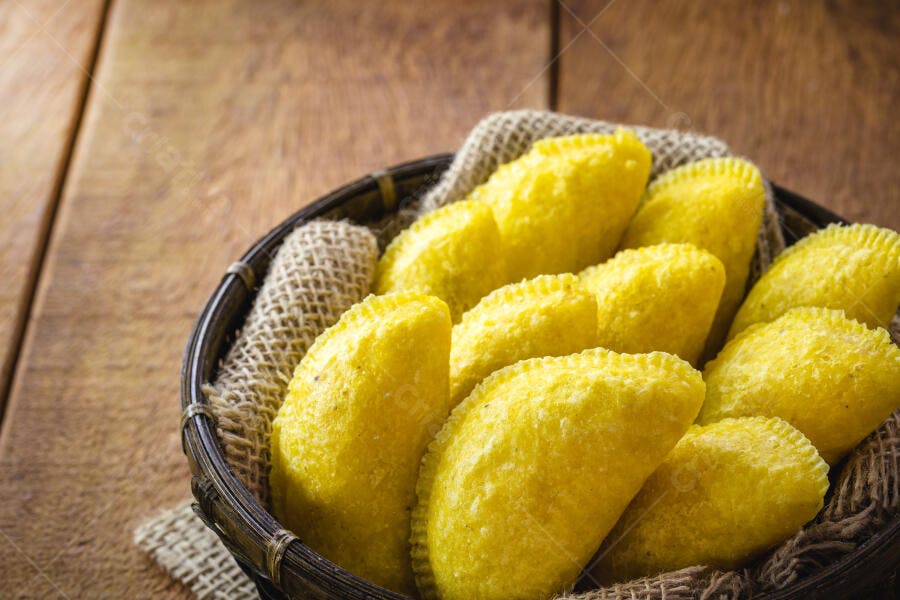 Pastel frito amarelo em cesta rústica de madeira na mesa
