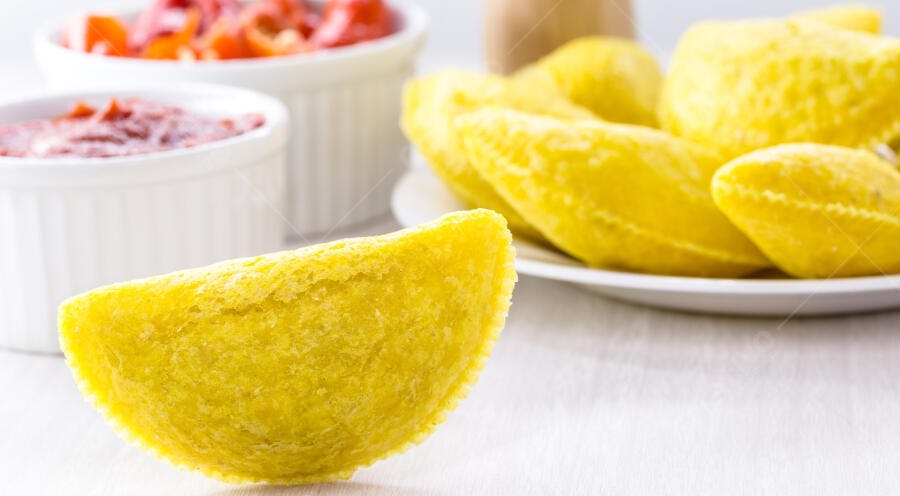 Pastel frito amarelo com molho vermelho e pimentões frescos