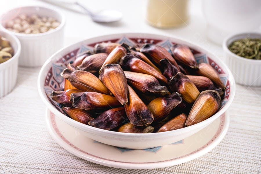 Pinhões castanhos em tigela decorada sobre mesa clara