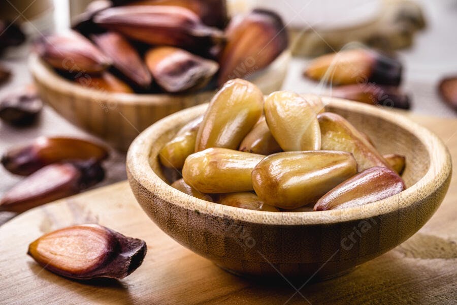 Pinhões descascados e com casca em tigelas rústicas de madeira