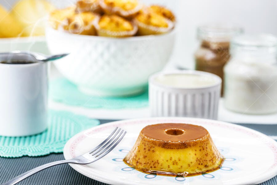 Pudim de leite cremoso dourado com calda de caramelo em mesa de café