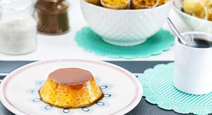 Pudim de leite com calda de caramelo em prato decorado e café