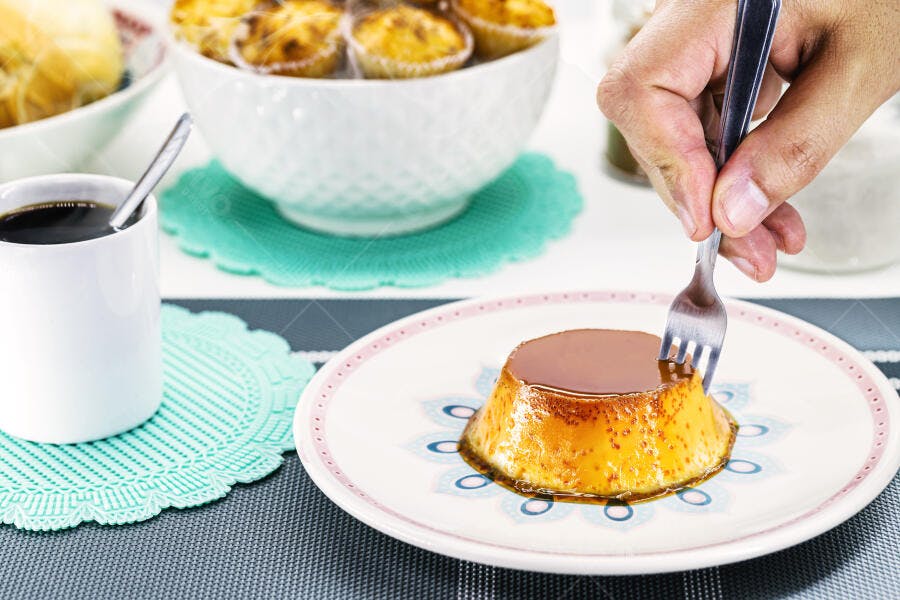 Pudim de leite condensado caramelo sendo servido em mesa de café da manhã