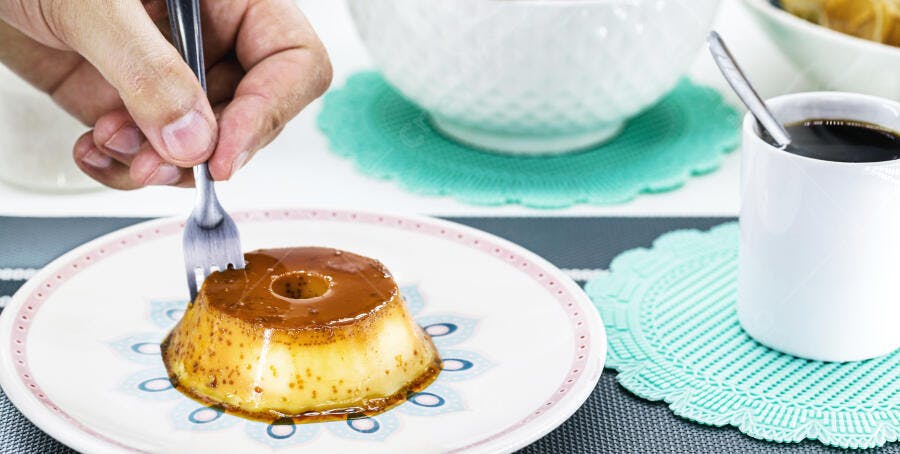 Pudim de caramelo em prato decorado com café da manhã e mão com garfo