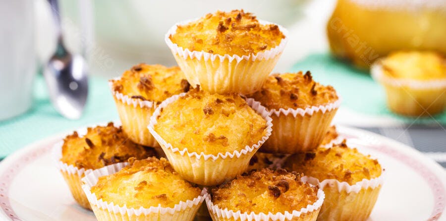 Cupcakes de coco dourados empilhados sobre mesa em ambiente claro