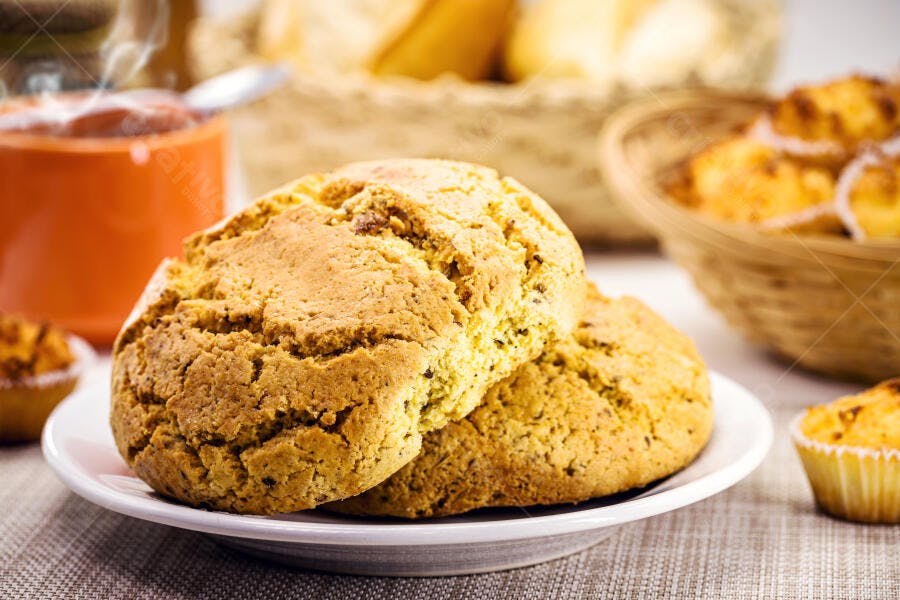 Biscoitos caseiros dourados em prato branco com café e muffins