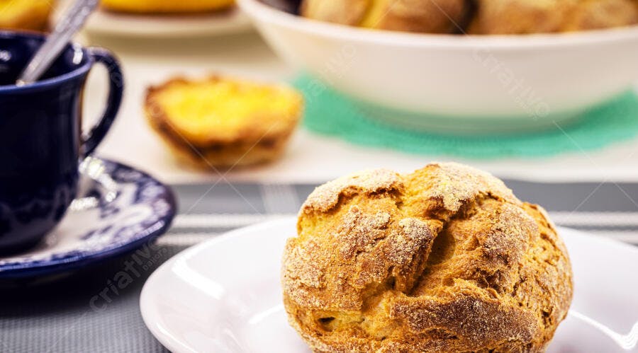 Pão de milho rústico em prato branco com xícara de café e pastel de nata