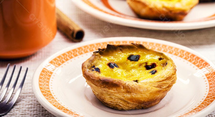 Pastel de Nata português tradicional em prato branco com café e canela