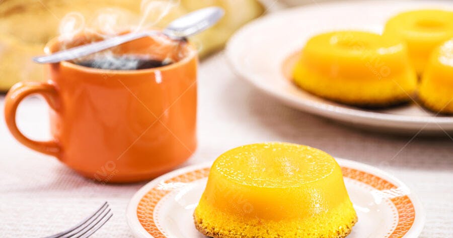 Pudins de quindim amarelos e café fumegante em caneca laranja para o café da manhã