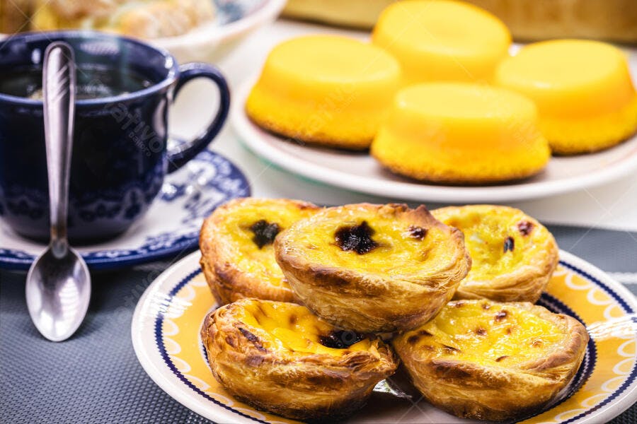 Pastéis de Nata tradicionais em prato com chá e doces portugueses