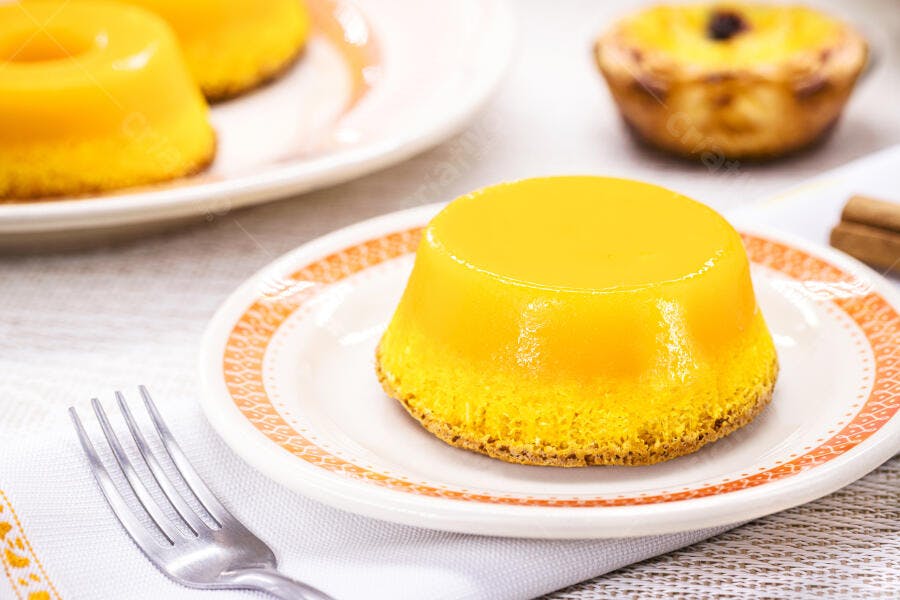 Quindim amarelo brilhante e pastel de nata em mesa de café da manhã